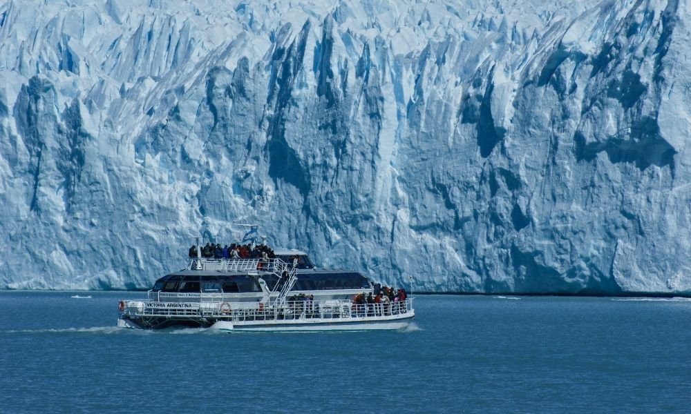 Small electric boat crossing a still Arctic fjord surrounded by snow-covered mountains in Norway