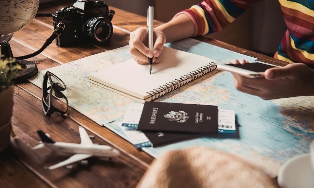 Traveler planning a Kyoto trip with a map, notebook, and travel guide at a café table.