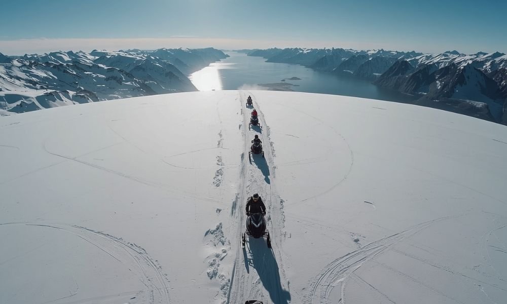 Snowmobiles crossing a high Arctic plateau with a fjord valley below in Tromsø Norway