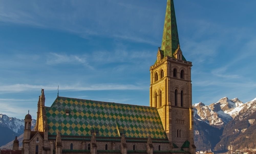 Bolzano Cathedral Gothic spire and distinctive diamond tile roof with Dolomite mountains behind, Piazza Walther South Tyrol Italy