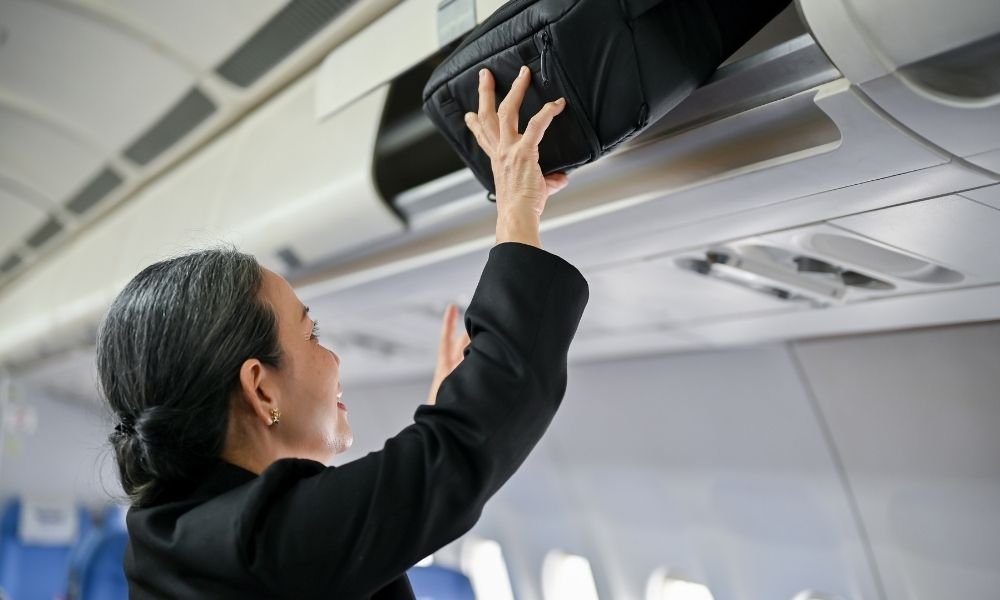 Traveller lifting a 40-litre carry-on backpack into an airplane overhead storage bin