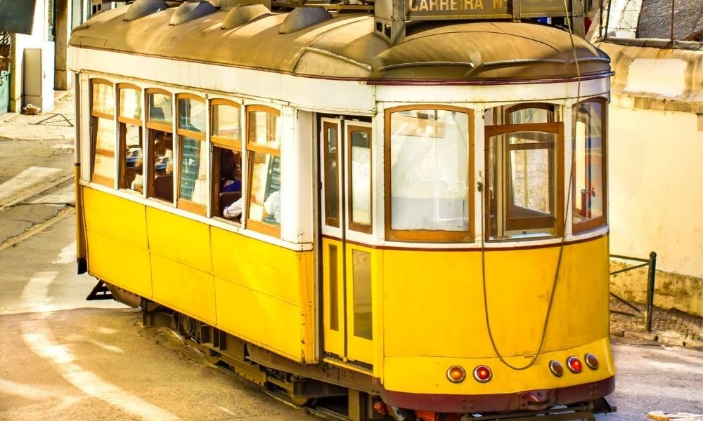 Tram 28 yellow tram passing Alfama rooftops in Lisbon A clean shot, ideally golden hour, contrasting with image 2