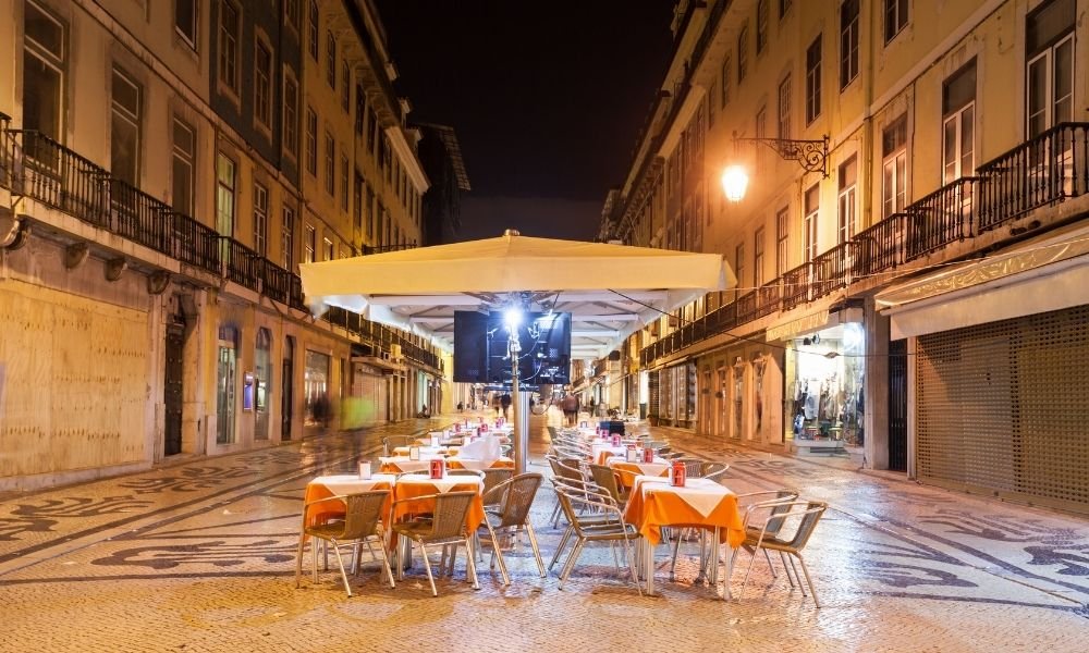 Evening street scene in Chiado neighborhood Lisbon with outdoor cafe tables and tiled buildings