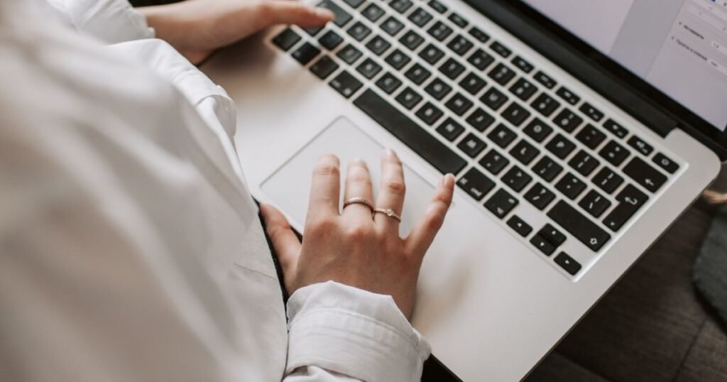 A first time traveler verifying a hotel booking website URL on a laptop to avoid travel scams
