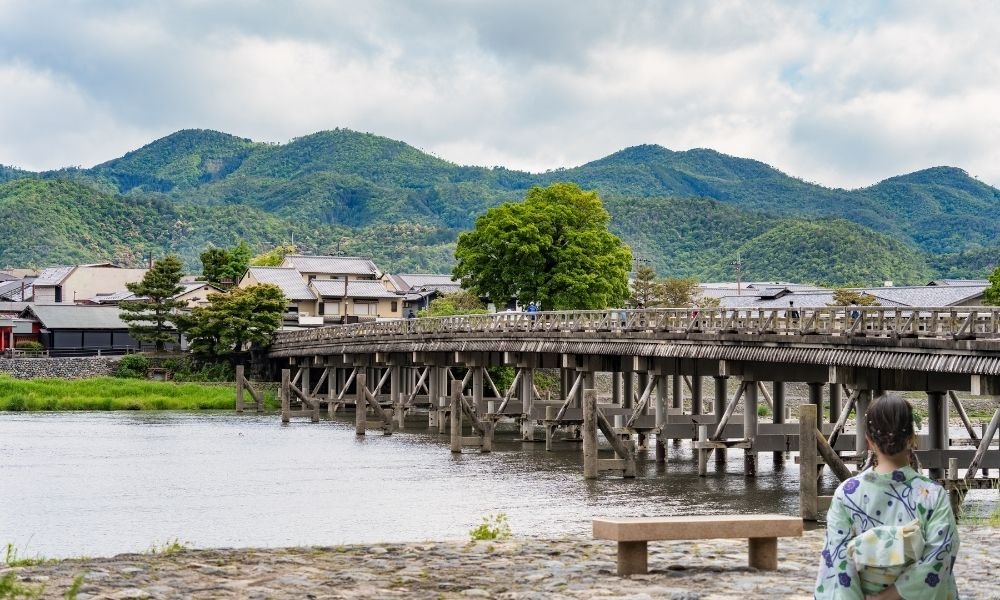 Togetsukyo Bridge crossing the Katsura River in Arashiyama with mountain hills and green trees visible on both sides