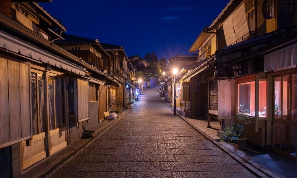 Traditional wooden machiya townhouse in Kyoto Higashiyama at dawn, narrow street, stone pavement, morning glories in a pot by the door, no people