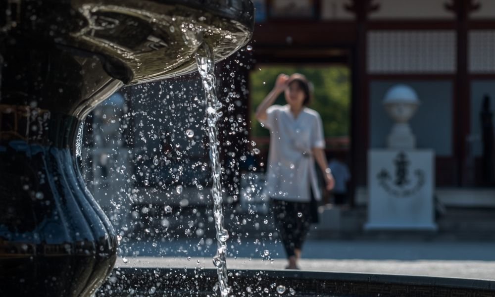 `Traditional purification fountain with wooden ladles at a Kyoto shrine entrance`