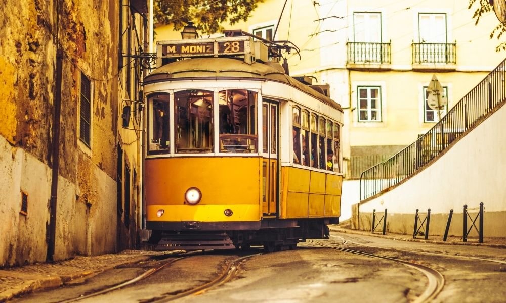 Tram 28 yellow tram navigating narrow street in Alfama Lisbon Portugal