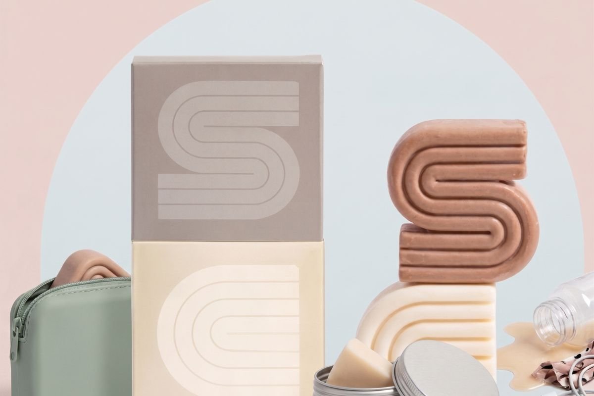Two unbranded cardboard boxes and two matching stacked solid shampoo and conditioner bars in tins and as unwrapped bars.